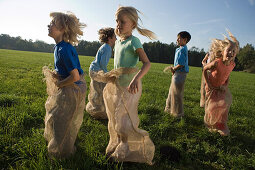 Group of children having a sack race, children's birthday party