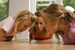 Drei Mädchen spielen Wattebausch blasen, Kindergeburtstag