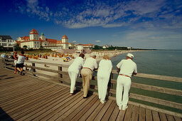 Vacationers standing on beach bridge and looking over beach and spa hotel, Binz, Ruegen, Mecklenburg-Western Pomerania, Germany