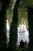 Father and Child watching sailing boats on the island Frauenchiemsee, Fraueninsel on Lake Chiemsee, Bavaria, Germany