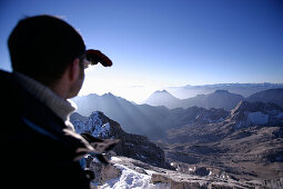 Man at the summit of the Zugspitze in the morning looking over Reintal, Bavaria, Germany