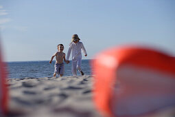 Mädchen und Junge laufen Hand in Hand über den Ostseestrand