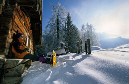 Hiker with snowshoes during break at cabin, Priesbergalm, Berchtesgaden Range, Upper Bavaria, Bavaria, Germany