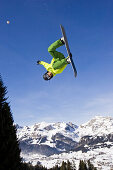 A young man on a snowboard doing a backflip in the funpark snowland, Wildhaus, Toggenburg region, East Switzerland, St. Gallen, Switzerland, Alps, Europe
