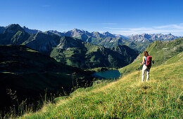 hiker above lake Seealpsee with view to Allgäu range, Allgaeu, Swabia, Bavaria, Germany