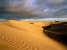Couple walking through the dunes of Maspalomas, nature reseve, Gran Canaria, Canary Islands, Spain