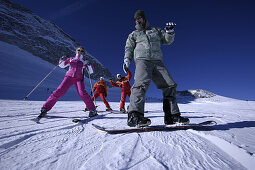 Two people having ski and snowboard lessons with ski instructors, Hintertux Glacier, Tyrol, Austria