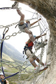 Three men climbing in a spiders web at Crazy Eddy in Silz, Haiming in the background, Tyrol, Austria