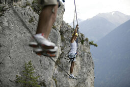 Two men climbing on a rope bridge at Crazy Eddy in Silz, Haiming in the background, Tyrol, Austria