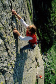 Junge Frau klettert an Felswand, Urner Alpen, Kanton Uri, Schweiz, MR