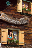 Young woman looking out of a window at Lammersdorfer Hut, 1650 m, Lammersdorf near Millstatt, Carinthia, Austria