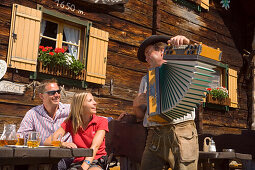 Couple listening to man playing accordion, Lammersdorf hut, Lammersdorf near Millstatt, Carinthia, Austria