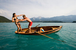 Junger Mann schubst Freundin vom Ruderboot ins Wasser, Faakersee, Kärnten, Österreich