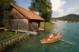Young couple in a rowboat on Lake Faak near a boathouse, Carinthia, Austria
