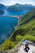 People staning on vantage point at Monte San Salvatore (912 m) and looking over Lake Lugano and Lugano, Ticino, Switzerland