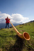 Man playing a alphorn at Bussalp (1800 m), Grindelwald, Bernese Oberland (highlands), Canton of Bern, Switzerland