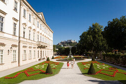 Tourists strolling through Mirabell garden, Hohensalzburg Fortress, largest, fully-preserved fortress in central Europe, in background, Salzburg, Salzburg, Austria