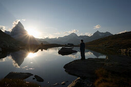 Eine Person beobachtet den Sonnenuntergang, Ostwand, Hoernligrat des Matterhorns, 4478 m, spiegelt sich im Riffelsee, Zermatt, Valais, Switzerland