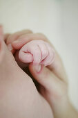 Close up of baby's and mother's hands holding each other