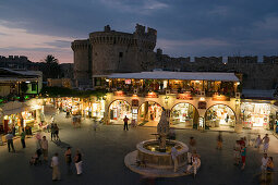 View over busy Platia Ippokratou with Thalassini Gate in background in the evening, Rhodes Town, Rhodes, Greece, (Since 1988 part of the UNESCO World Heritage Site)