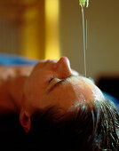 Ayurvedischer Stirn-Öl-Guß bei einer Frau, Teil einer ayurvedischen Massage, Wellness Anwendung in einem Hotel, Deutschland