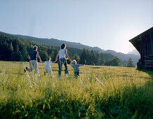 Family with two children running over mountain pasture, Leogang, Salzburg (state), Austria