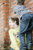 Two boys climbing over a wall
