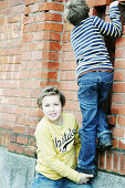 Boy giving friend a bunk-up over a wall