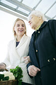 Young woman helps an elderly lady and carries the shopping