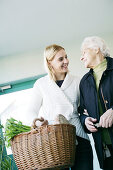 Young woman helps an elderly lady and carries the shopping