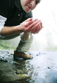 Mann trinkt Wasser am Fluß, Wellness, Natur, Gesundheit