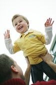 Father lifts son in the air, laughing