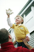 Father lifts son in the air, laughing