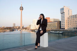 Junge Geschäftsfrau telefoniert im Medienhafen von Düsseldorf, Fernsehturm, Rheinturm, neuer Zollhof, Landeshauptstadt von NRW, Deutschland