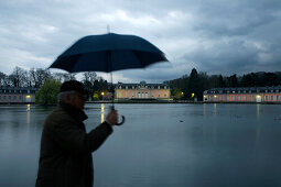 Man walking by Benrath castle holding umbrella, Düsseldorf, state capital of NRW, North-Rhine-Westphalia, Germany