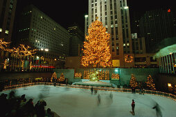Rockefeller Center at night with Christmas decorations, Lower Plaza with Prometheus, People ice scating in the foreground, New York City, USA