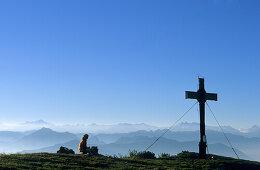 Hiker at cross on summit of Sonnwendjoch, Rofan range, Tyrol, Austria