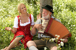 Mature man playing melodeon, woman clapping hands