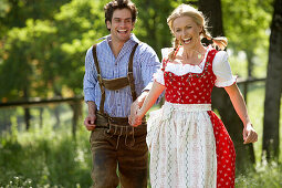 Couple running hand in hand over a meadow