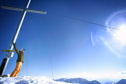 Cheering skier near summit cross, Grawand peak, Schnals Valley, Oetztal Alps, South Tyrol, Italy, MR