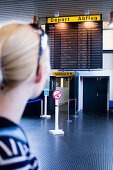 Junge Frau blickt auf Informationstafel am Flughafen, Luxemburg