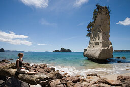 Frau entspannt sich an der Cathedral Cove, nahe Hahei, Coromandel Peninsula, Nordinsel, Neuseeland