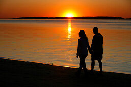 Couple walking along the beach at sunset, Wellfleet Harbor, Cape Cod, Massachusetts, USA