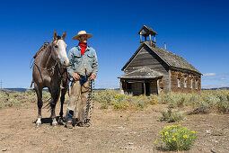 cowboy with horse at old schoolhouse, wildwest, Oregon, USA