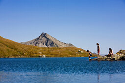 Three young people at lakeshore of Laghi della Valletta, Gotthard, Canton of Ticino, Switzerland