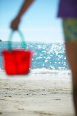 Girl (4-5 years) carrying bucket along beach Kniepsand, Wittduen, Amrum island, North Frisian Islands, Schleswig-Holstein, Germany