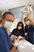 Zahnbehandlung, Zahnbehandlung beim Zahnarzt, Zahnarzt und Helferin beugen sich über den Patienten. Praxis Dr. Vesic, Hannover