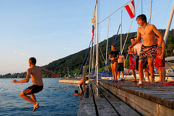 Junge Männer springen vom Bootssteg, Attersee, Salzkammergut, Salzburg, Österreich
