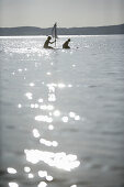 Two kids on a small raft with sail, Ammerland, Lake Starnberg, Bavaria, Germany