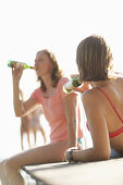 Zwei Frauen trinken Bier auf einem Holzsteg am Wörthsee, Bayern, Deutschland, MR